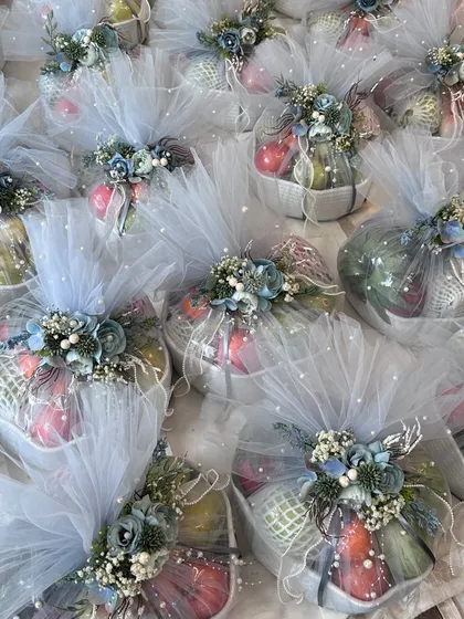 A sea of beautifully wrapped fruit baskets in a dusty blue theme, ready for a wedding celebration.