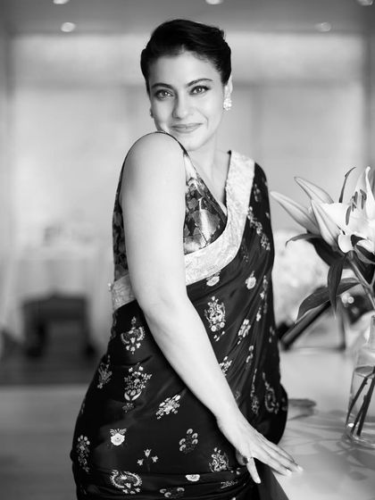 A timeless black and white portrait of Kajol, capturing her classic beauty in an intricately embroidered dark saree.