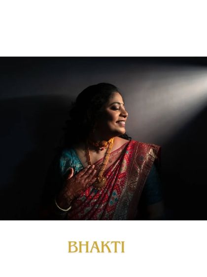 An artistic portrait of the bride from her engagement shoot. The dramatic lighting creates a beautiful contrast, emphasizing her joyful expression and the details of her traditional attire.