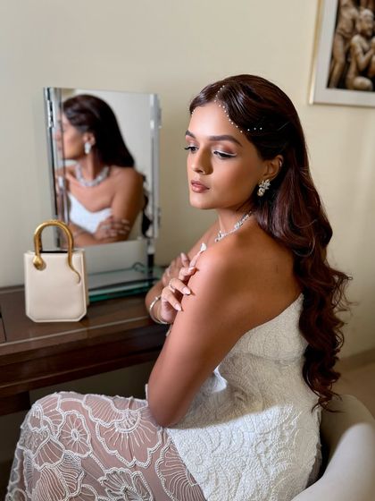 A side profile showcasing the soft glam makeup and delicate pearl hair accessories for this wedding guest.