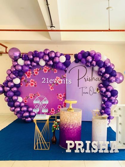 A wider view of the purple floral theme, showing the full balloon arch and marquee number.