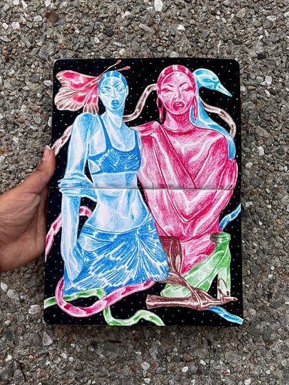Holding the sketchbook with the blue and pink figures.