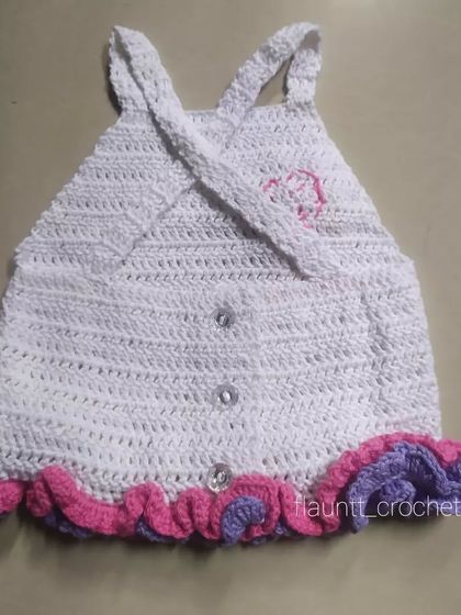 The back of the white ruffled top features a criss-cross strap design and button closures, ensuring a secure and adjustable fit.