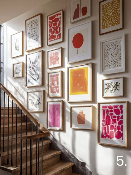 Infuse your stairway with energy through a bold and playful arrangement. This gallery features vibrant abstract prints in simple, light-colored frames, turning the wall into a focal point that is full of character and modern flair.