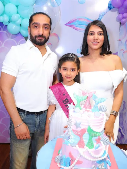 The cake cutting is a centerpiece moment, and we make sure it's perfect. Here, a happy family celebrates with a stunning, multi-tiered mermaid cake that perfectly matches the party's underwater theme.