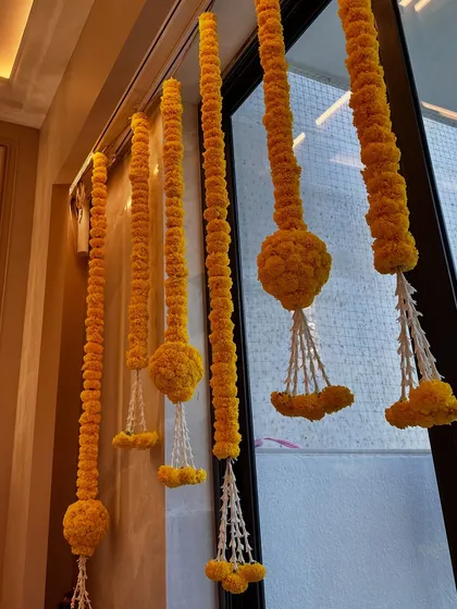 Classic marigold flower strings, or 'genda phool ladi', hanging in a doorway. The vibrant yellow color is a symbol of celebration and happiness in Indian culture.
