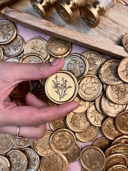 Our handmade wax seals are a signature touch of elegance. This close-up shows the intricate floral details embossed in rich, golden wax. Each seal comes with an adhesive back, making it easy to add a touch of artisanal luxury to your invitations, gifts, and cards.