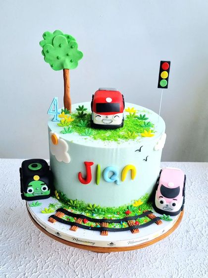 A Titipo the Little Train themed cake. This design includes a train track, traffic light, and the main characters sculpted from fondant.
