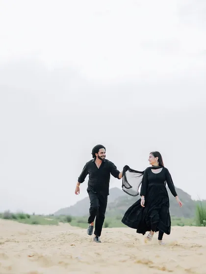 A playful and dynamic shot of the couple running through the sand, capturing a moment of carefree joy.