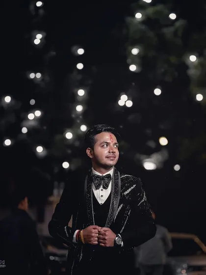 An outdoor groom portrait at night, with bokeh lights in the background. This creates a magical and celebratory atmosphere, perfect for capturing the groom's style during an evening event.