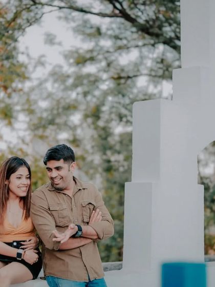 A candid moment between a couple at our Santorini-inspired set, featuring the iconic white bell tower structure. This captures a relaxed and happy interaction in a beautiful setting.