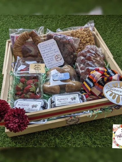A winter-themed hamper filled with seasonal dry fruits like walnuts and figs, fresh strawberries and mulberries, and a warm, colorful muffler.