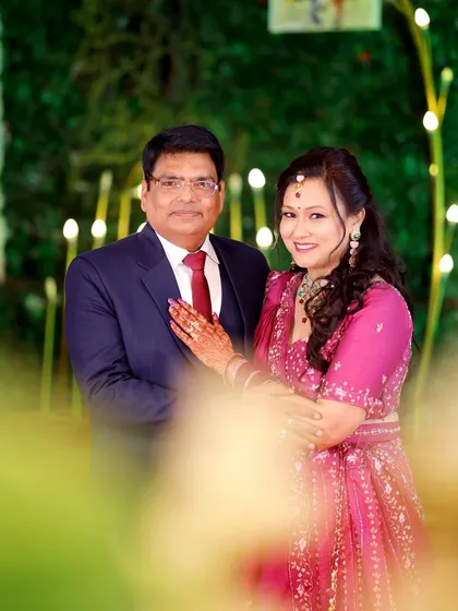 A beautifully framed portrait of the anniversary couple, using a soft foreground blur to create a sense of intimacy and focus.