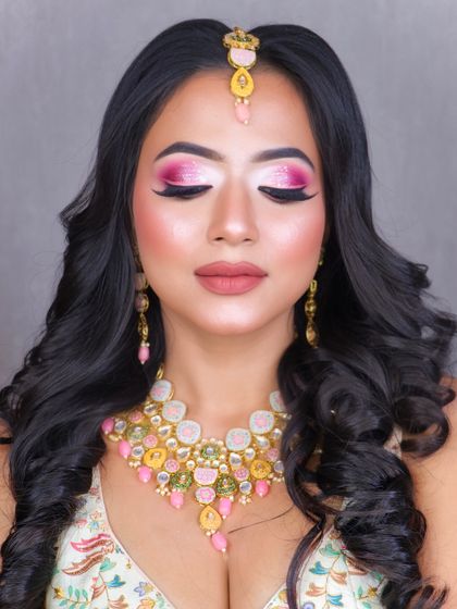 How gorgeous is this look? A beautiful party makeup with a vibrant pink cut crease, glowing skin, and soft curls, paired with meenakari jewelry.