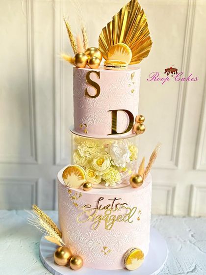 This is one of my most requested engagement cake designs. The floating tier is filled with flowers, and the cake is decorated with golden palm leaves, macarons, and the couple's initials for a modern, celebratory look.