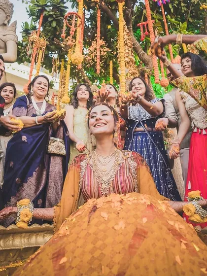 A moment of bliss for the bride during her Haldi ceremony, as loved ones shower her with flowers and blessings.