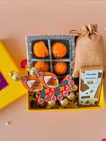 A closer look inside the yellow Diwali box, showing the detail on the Shubh Labh hangings and the delicious-looking laddoo candles.