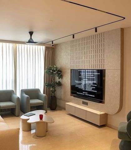 The living room of a home we designed at Oberoi Sky City, Borivali. The space features our custom upholstery on the sofas and armchairs in soft, muted tones, creating a modern and sophisticated atmosphere.