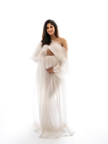 A full-length portrait of this gorgeous mommy-to-be in a sheer white gown. Her joyful smile and the simple, bright setting make this a truly beautiful memory.