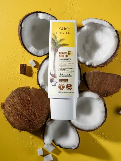 A vibrant flat lay for Taupe's 'Heal & Shield' sunscreen. By incorporating the core ingredient, coconut, we tell a visual story about the product's natural formulation. This style of ingredient-focused product photography is effective for clean beauty brands.