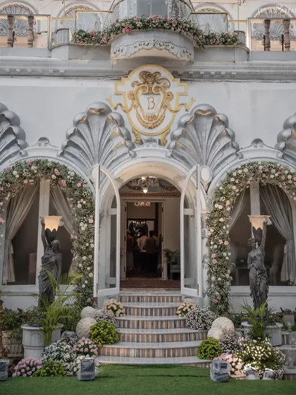 The grand entrance of Birla House adorned with arches of pink and white flowers, setting a tone of understated elegance for the wedding celebration.