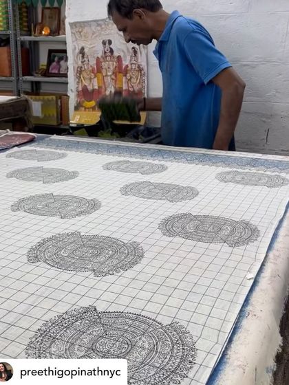 A master printer at work on a custom saree, with a calendar of deities watching over him. This blend of the sacred and the everyday is part of the unique atmosphere of our studio.