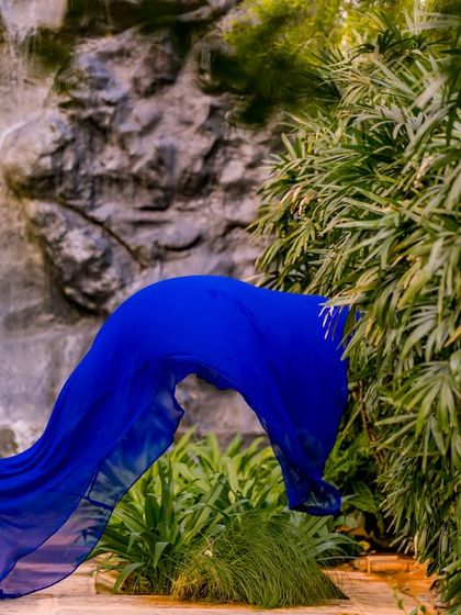 A dramatic shot of a flowing blue gown in front of the waterfall, creating a powerful and beautiful image.