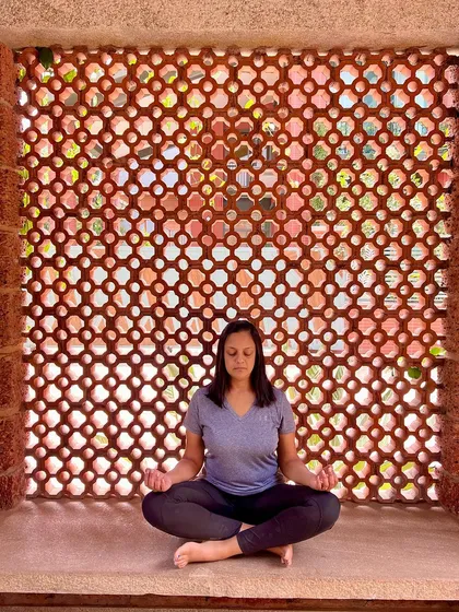 True quiet is found within. Here, a practitioner sits in Sukhasana (Easy Pose) for a moment of meditation against the beautiful, earthy backdrop of our retreat center's jali wall. This image reflects the importance we place on creating serene spaces for introspection and cultivating Sakshi Bhava, the state of the detached witness.