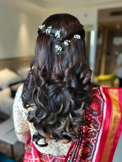 A simple yet elegant half-up hairstyle with beautiful curls, decorated with sprigs of baby's breath for a delicate touch.