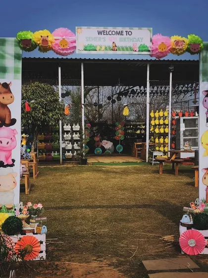 The main entrance gate to the farm-themed birthday party. The arch is topped with a "Welcome" sign and decorated with pom-poms and animal illustrations.