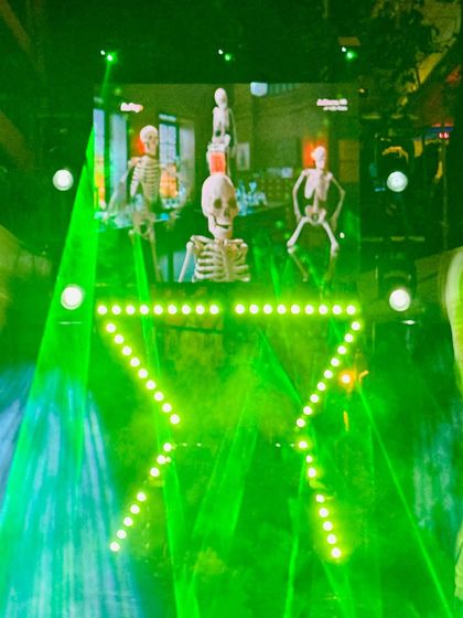 The compact DJ setup illuminated with vibrant green laser and LED lights. This shows how different color schemes can be used to match the theme of any event, from a Haldi to a Halloween party.