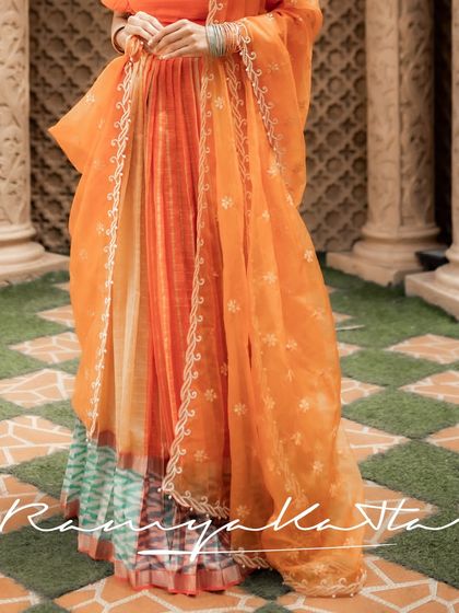 The full silhouette of the peach-orange silk half saree, showing the beautiful combination of the multi-hued skirt and the sheer embroidered dupatta.