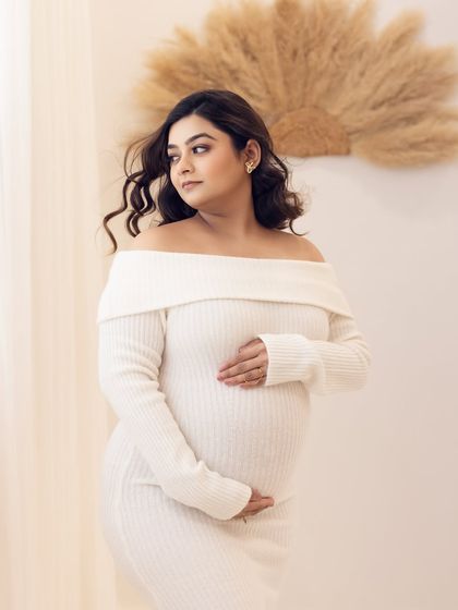 A thoughtful and serene portrait, with the mom-to-be looking out, bathed in soft studio light.