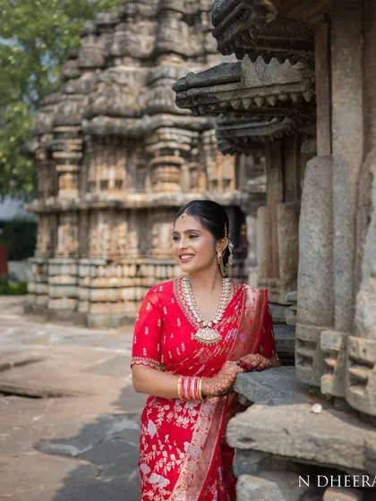 A candid shot of a bride in her red saree, showcasing the elegance of the full ensemble in a natural setting.