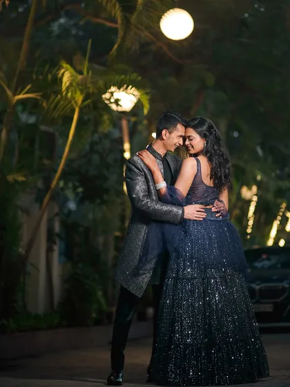 A full-length shot of the couple in a tender embrace, surrounded by the warm glow of evening lights. The bride's sparkling gown and the romantic setting make this a truly cinematic portrait.