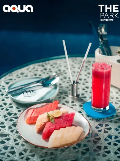 A healthy and refreshing fruit platter and juice at a poolside table. A perfect light snack to enjoy while lounging at Aqua.
