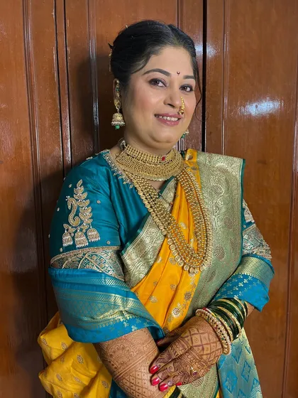 A happy portrait of the bride, showcasing the flawless makeup and traditional gold jewellery.