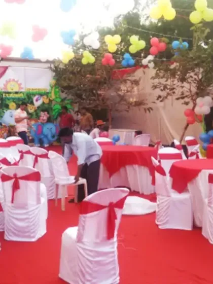An outdoor birthday party setup with a jungle theme backdrop and colorful balloons. I also arranged the guest seating with red and white chair covers and table linens.