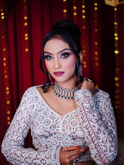 A close-up shot against a dramatic red backdrop, highlighting the contrast with the soft lavender outfit.