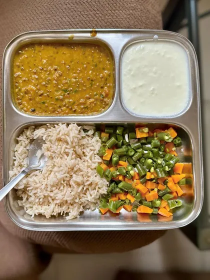 A simple vegetarian meal of brown rice, dal, mixed vegetables, and curd. This is a perfect example of a balanced and easy-to-make lunch.