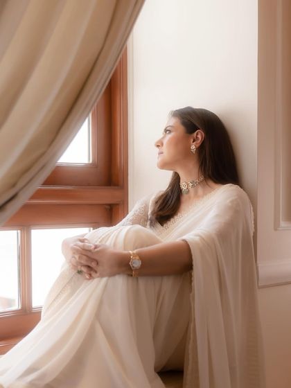 Another pensive moment by the window, with the natural light creating a soft glow on the white saree.