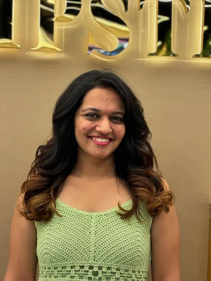 A happy client showing off her new hair color, a beautiful ombre effect with dark roots and lighter, curled ends.