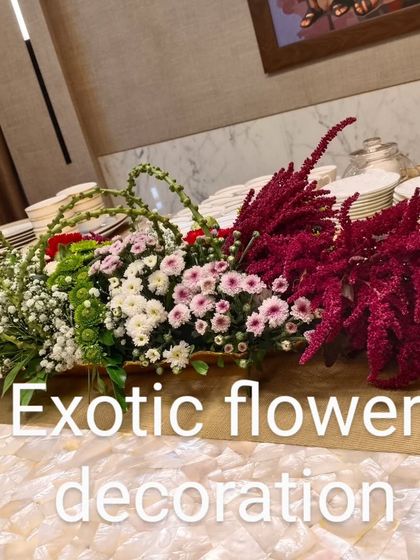 A long, boat-shaped centerpiece filled with a beautiful mix of red, pink, and white flowers. This type of arrangement is ideal for long rectangular dining tables.