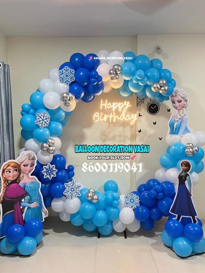 A Frozen-themed ring decoration. The blue, white, and silver balloons are accented with snowflake cutouts and character standees of Elsa and Anna.