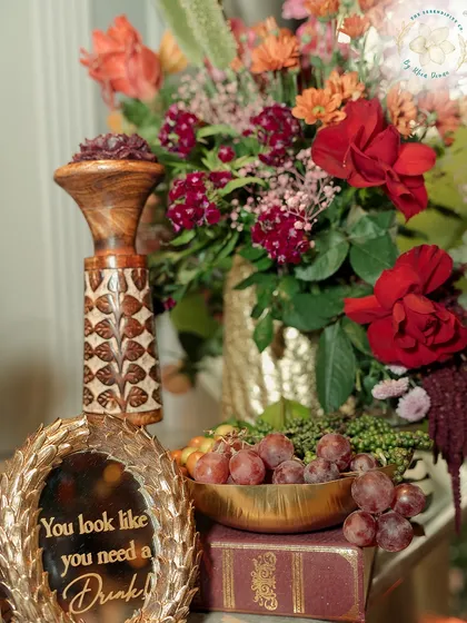 A close-up of the bar decor, featuring a custom-engraved mirror, vintage books, and a bowl of fresh grapes. These small, thoughtful touches create a rich, layered look.