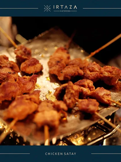 Juicy Chicken Satay skewers being grilled to perfection. This is a popular live station item that fills the air with an irresistible aroma and offers guests a taste of Southeast Asian cuisine.