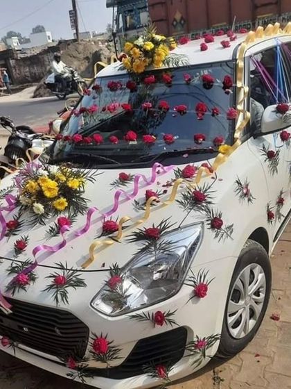 A fun and festive car decoration with small bouquets of yellow and red flowers, accented with colorful ribbons.