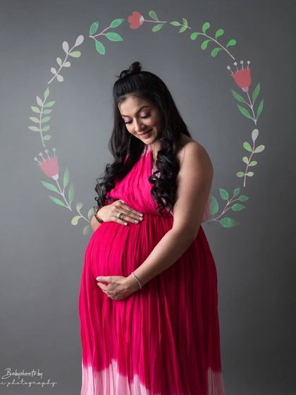 A close up of the mother to be in her beautiful pink gown, looking down at her bump. The painted floral background adds a unique, artistic element to the shot.