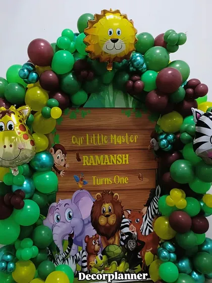 A closer look at the personalized jungle theme backdrop for Ramansh's first birthday. The vibrant greens and cute cartoon animals make it a cheerful and inviting centerpiece for the party.