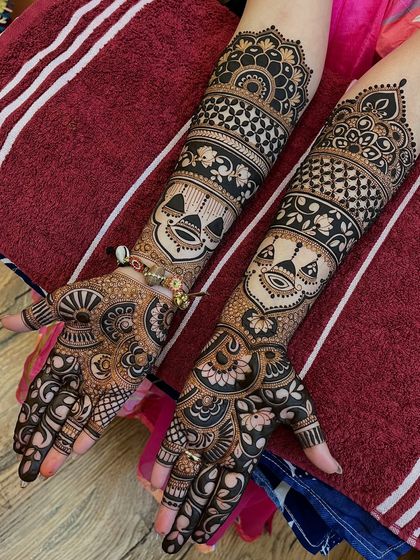 A full view of the unique mask-themed mehandi, showing how the design extends up the arms.